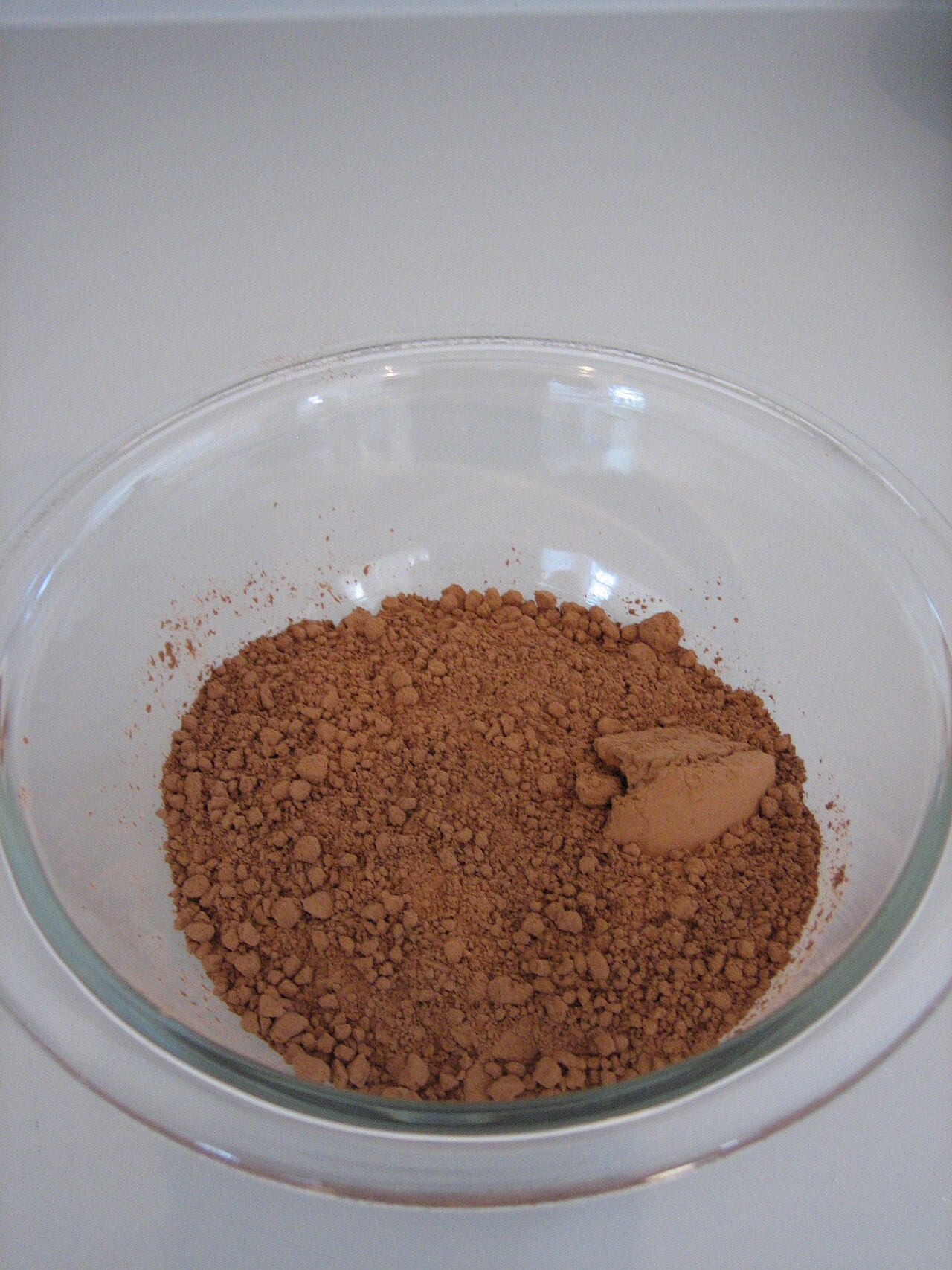 Brown cocoa powder in a clear glass bowl.